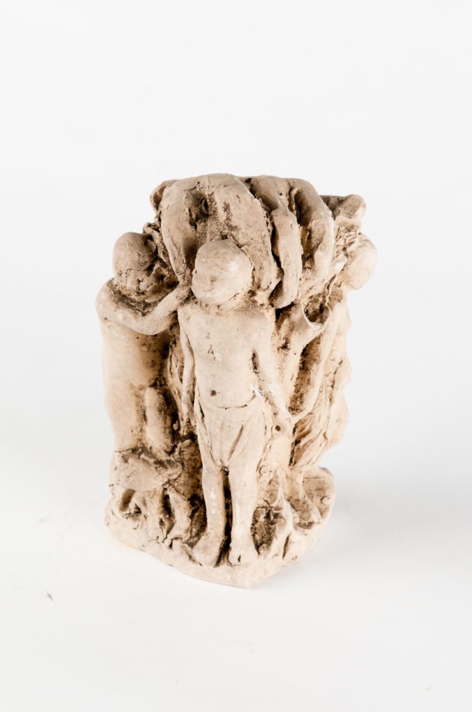 Small clay sculpture of several child like figures under a large hand that is reaching out to them.
