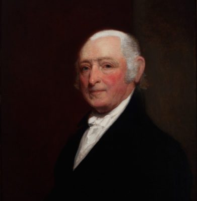 Realistic painting of an older white man with short white hair and a ruddy complextion. He is depicted from the chest up, wearing a black coat with wide lapels and a white undershirt. The background is primarily solid brown-red.