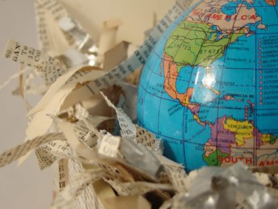 Photograph of a blue globe of the Earth on the right with about half of it off the scene, and surrounded by shredded paper