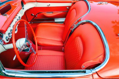 Photograph of a red convertible car interior with red leather seats, silver metal trim, and red steering wheel.