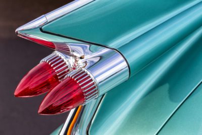 Photograph of a 1950s car tail light, with a bright blue body, angled tail end and jutting out red break lights.