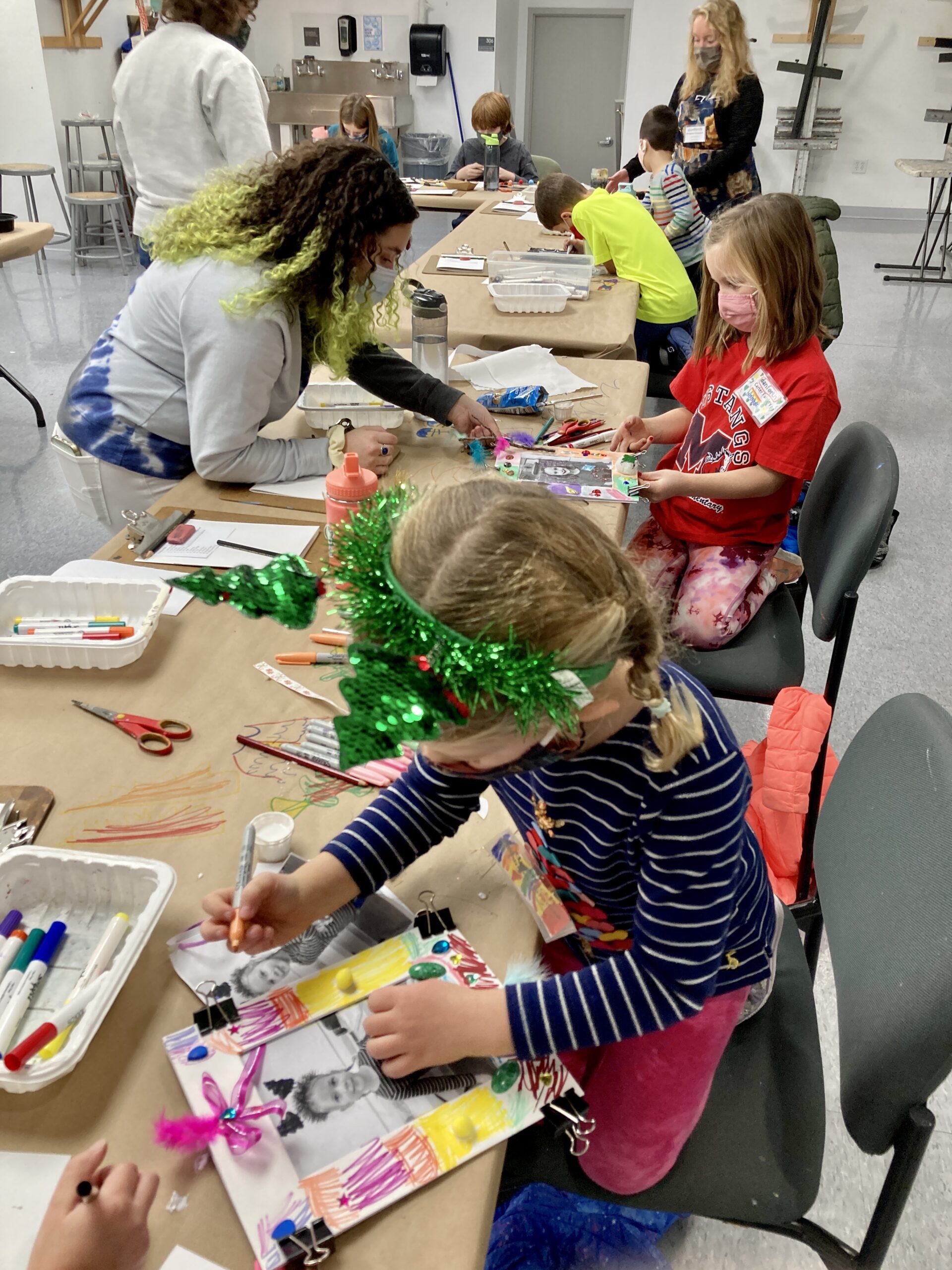 Photograph of young kids at a long table creating colorful cardboard picture frames.