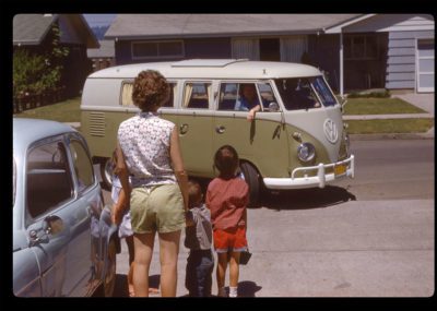 Two old colored photographs side by side. On the left is a VW bus in green and white pulling up to a driveway with a woman and three kids standing looking at the van. On the right is an interior of a call on a highway from the back seat looking at a teen sitting backwards in the front seat with a cigarette in his mouth.