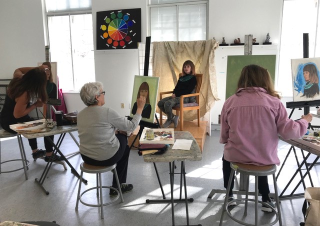 Photograph of a portrait class painting at easel with model