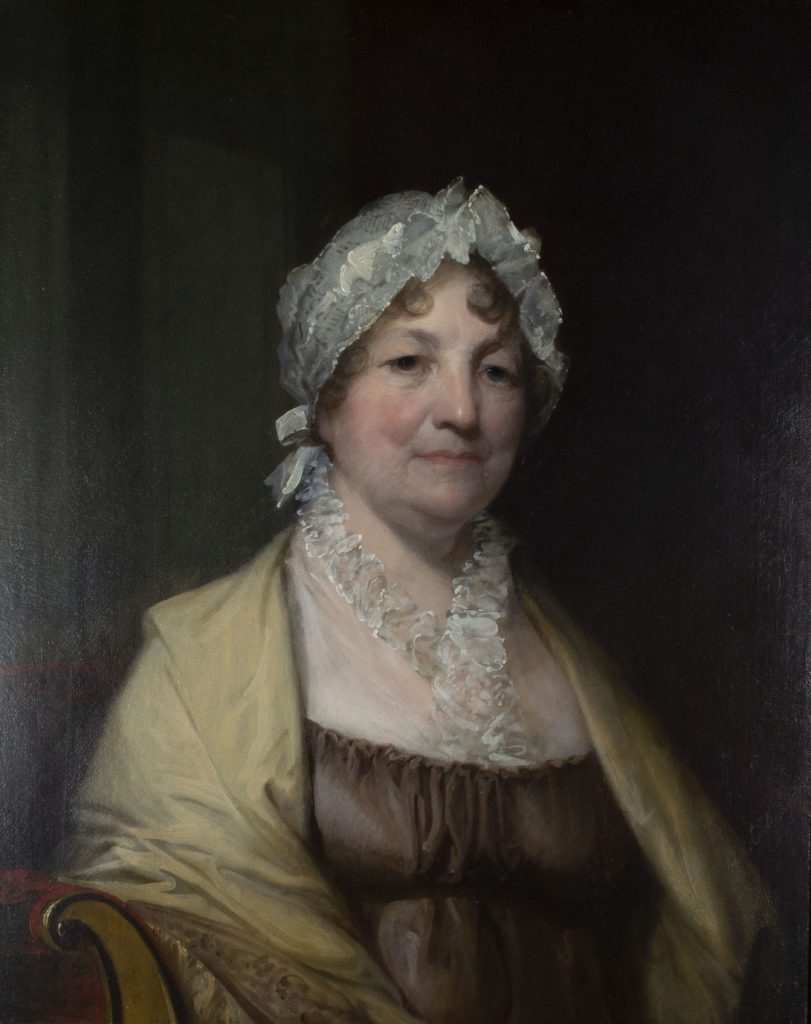 Portrait painting of an older woman, seated from the waist up, with light skin, wearing a brown empire dress and tan shawl and lacy top. Her light brown hair is under a white lacy cap.