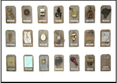 Photograph of a sculpture piece with three rows of wooden tags each with a different object and a different label underneath of an action word.
