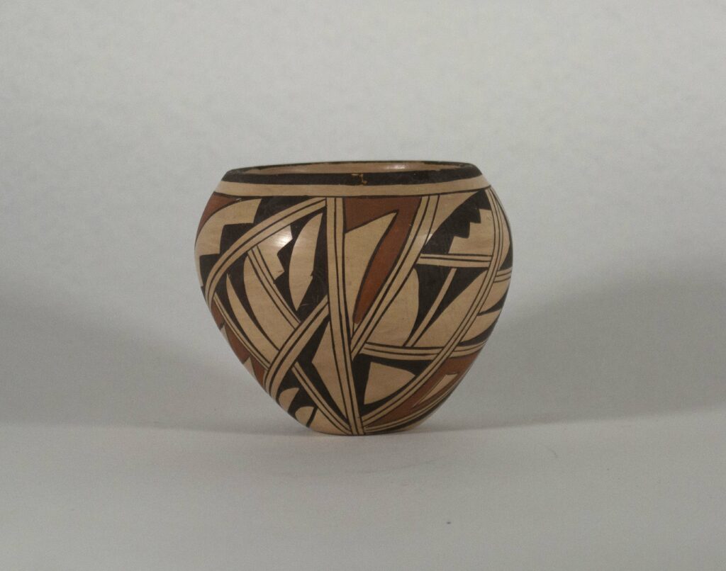 Small pot with a tan background and geometric shapes painted in black and red.