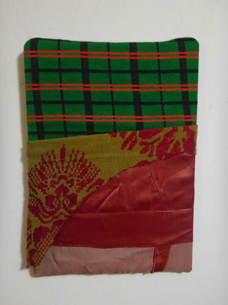 Photograph of a fabric rectangle with red and brown at the bottom and on top with a green, black, and red checkered fabric.