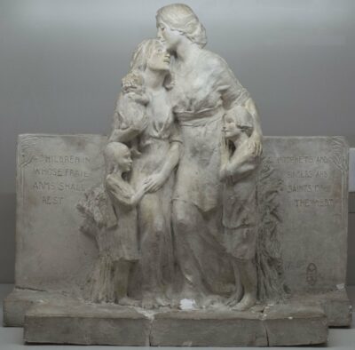 Photograph of a sculpture with a flat background, with a group of five females, two adults and three kids, embracing.