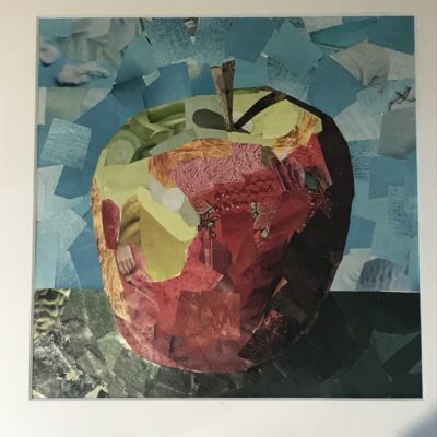 Paper collage of a red apple with a blue sky and grey base.