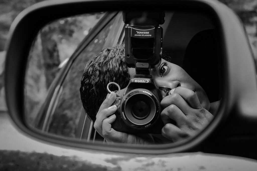 Photograph in black and white of a close up car side view mirror