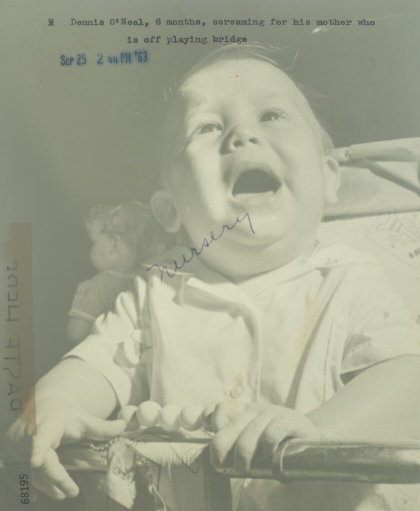 Black and white photograph of a baby crying, looking upwards. There is printed text around it.