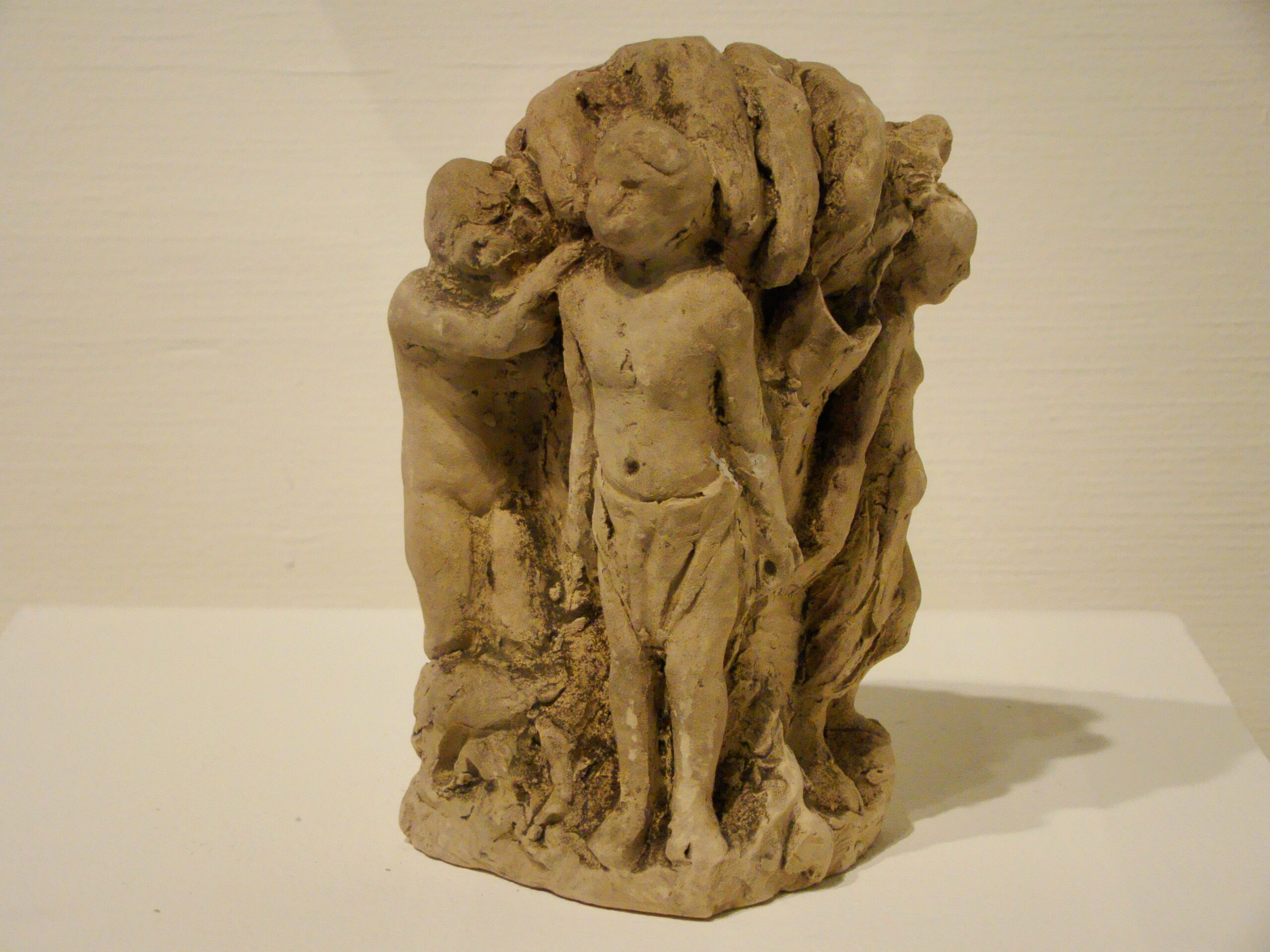 Small clay sculpture of several child like figures under a large hand that is reaching out to them.