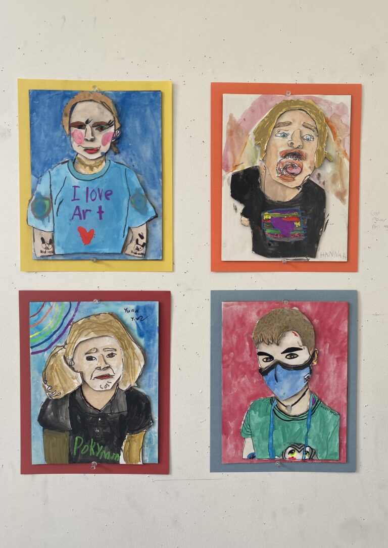 Display of children's self portrait paintings with collage elements making up their self portrait.