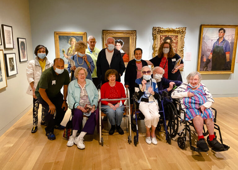 Photograph of a group of senior citizens in a museum gallery posing for a group photo.