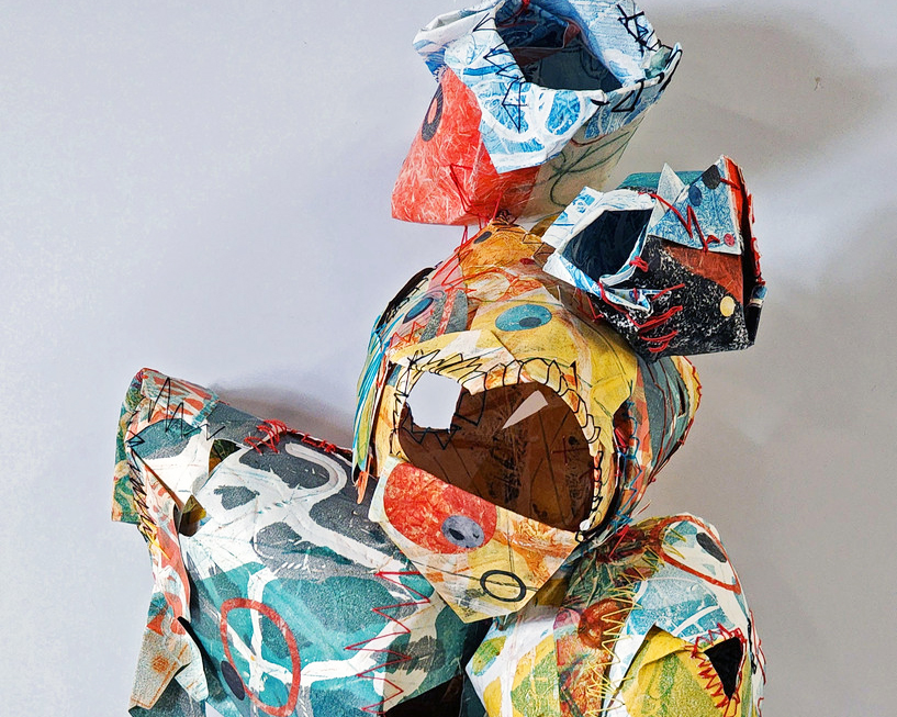 Feature image Hanging paper sculpture of amorphous rounded shapes connected together. The patterns are busy with primary colors of blue, red, yellow, teal, and white. Thick threads hold the paper in their shapes in colors of black, red, yellow, and teal.