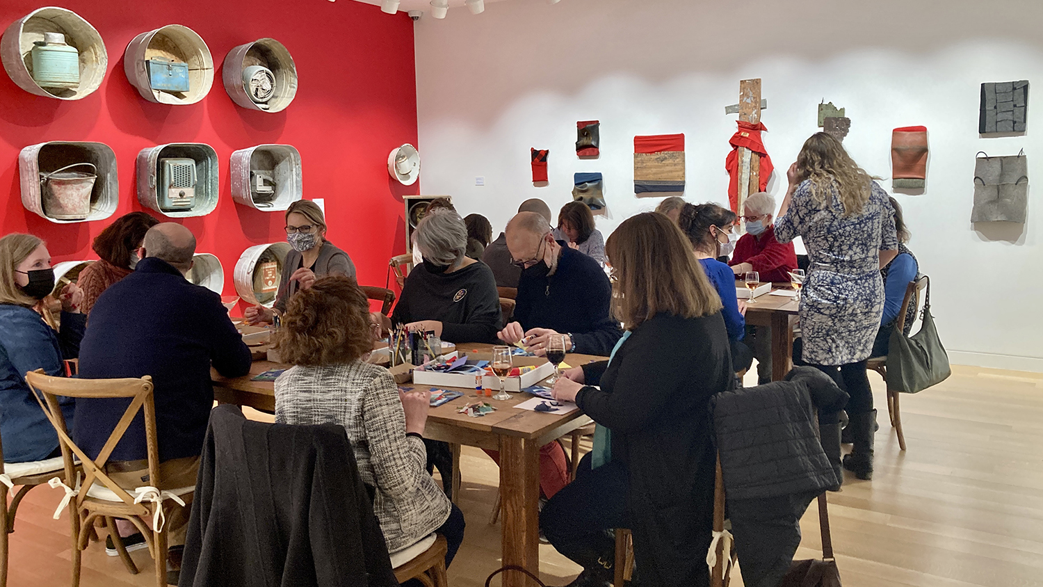 Photograph of a group of people around two long galleries in an exhibition room. They are doing crafts.