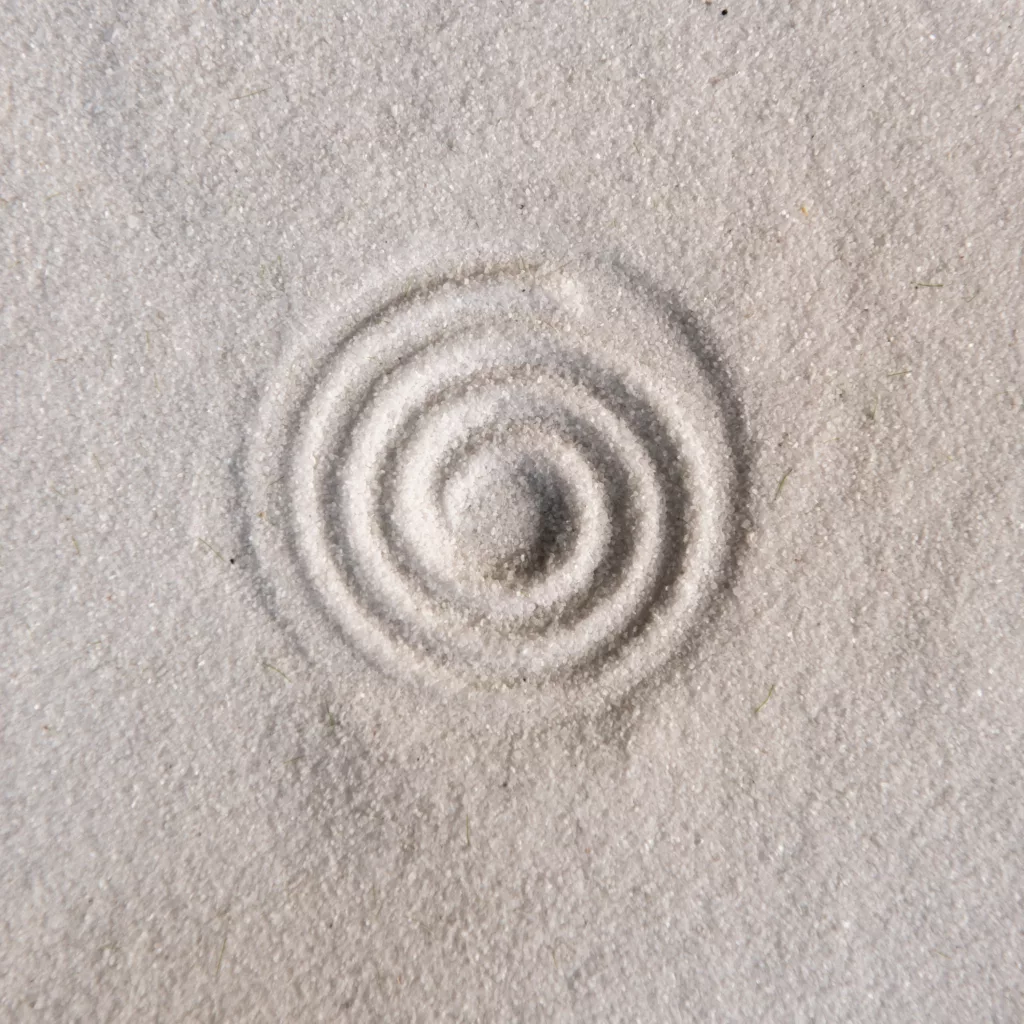 Photograph of sand with circles spiraling in the center .