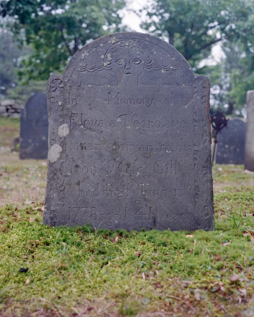Photograph of a tombstone with an angel head carved into the top