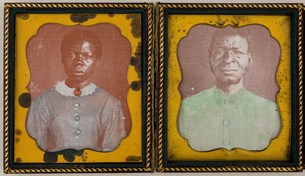 Photograph of two photos inside a small case. The photo on the left is a woman in a blue dress. The photo on the right is a man in a bright green shirt.