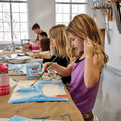 Two girls paint in an art class.