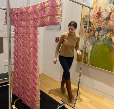 Woman installs pink dress in museum gallery.