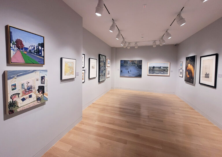 Photograph of a gallery installation with grey walls. Artwork is hung on the three visible walls.