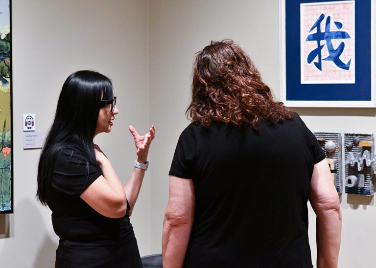 Photograph of two women talking about a photograph in a gallery room.