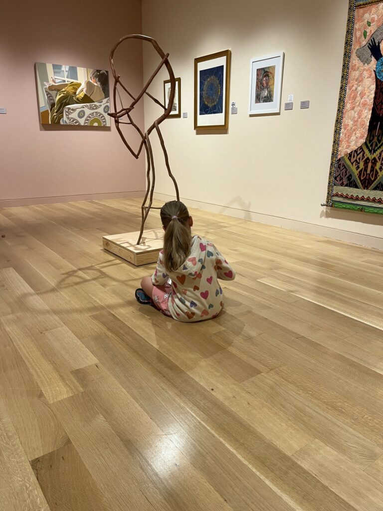 Photograph of a young girl in a museum gallery drawing from a sculpture